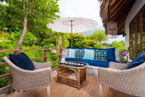 a patio with a couch and two chairs and an umbrella at The Fisherman's Villas in Koh Tao