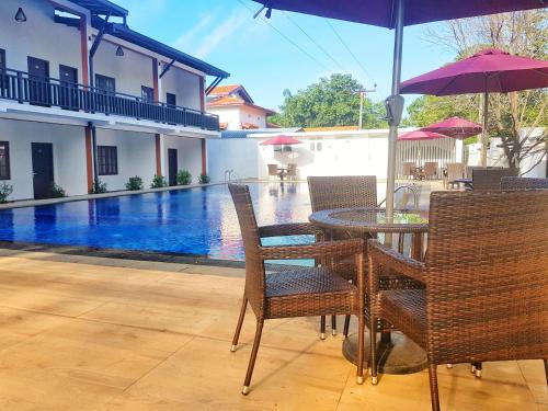 a table and chairs with an umbrella and a swimming pool at Livinya Holiday Resort in Kataragama