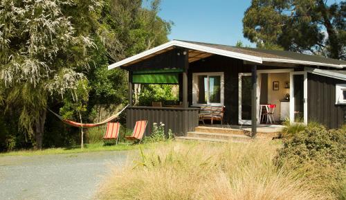 a house with chairs and a hammock in front of it at The Apple Pickers' Cottages in Mapua