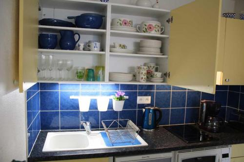cocina con fregadero y pared de azulejos azules en La Marinière, en Mesquer