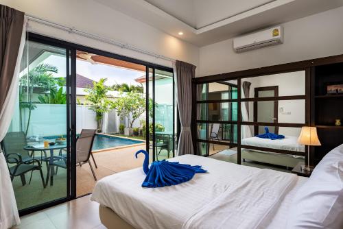 a bedroom with a bed and a balcony with a pool at Big Buddha View 3br Pool Villa by Intira Villas in Rawai Beach