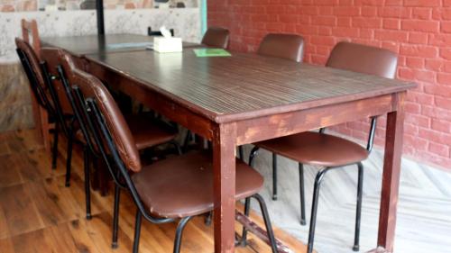 a wooden table with chairs and a brick wall at Harry Guest House & Restaurant in Pokhara