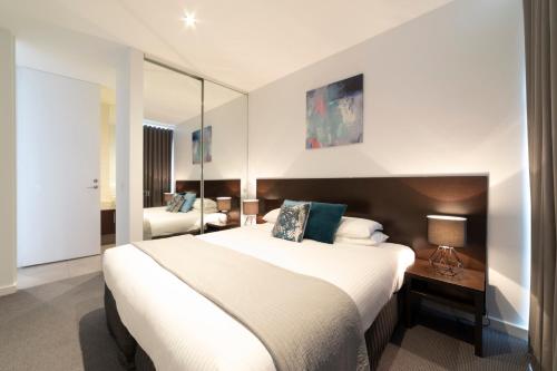 a hotel room with a large bed and a mirror at The Dolphin Apartments in Apollo Bay