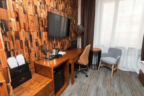 a hotel room with a desk and a television on a wall at East Astana Hotel in Astana