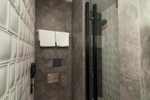 a bathroom with a shower with towels on the wall at East Astana Hotel in Astana
