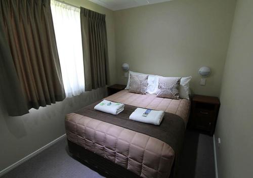 a bedroom with a bed with two towels on it at NRMA Atherton Tablelands Holiday Park in Atherton
