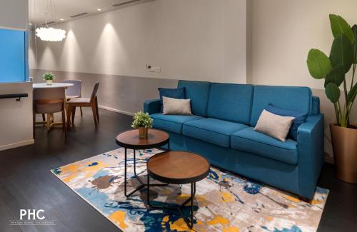 a living room with a blue couch and tables at Ropewalk Piazza Hotel Managed by The Ascott Limited in George Town