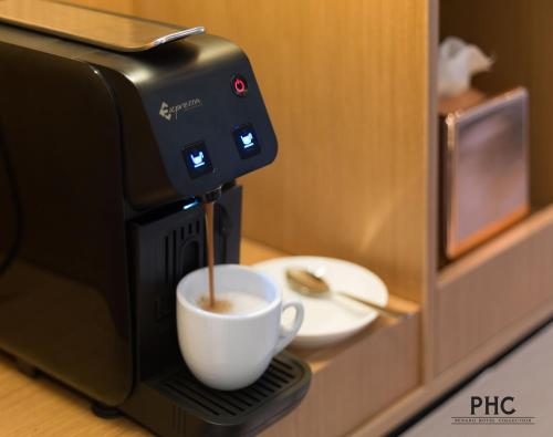 a coffee maker is making a cup of coffee at Ropewalk Piazza Hotel Managed by The Ascott Limited in George Town