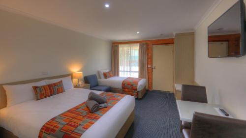 a hotel room with two beds and a desk at Moama Central Motel in Echuca