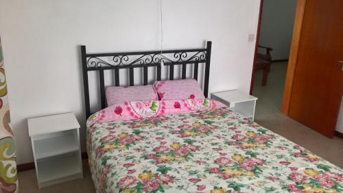 una camera da letto con un letto con copriletto floreale e cuscini rosa di Bodhee Villa a Grand Baie