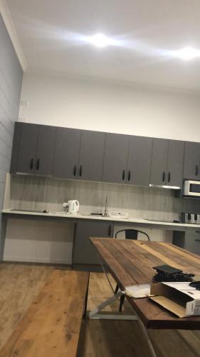 a kitchen with a wooden table and a counter top at Bunk Inn Hostel in Bundaberg