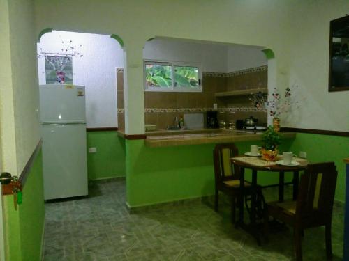 a green kitchen with a table and a refrigerator at Casa Palagui Colonial in Valladolid