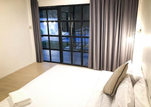 a bedroom with a bed and a large window at Ban Rub Lom Pool Villa 3 difference villas in Rayong