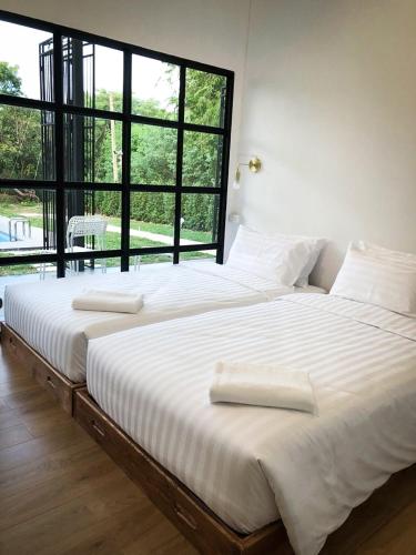 two beds in a room with a large window at Ban Rub Lom Pool Villa 3 difference villas in Rayong