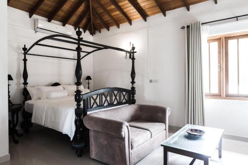a bedroom with a bed and a chair and a table at Villa White Queen in Galle