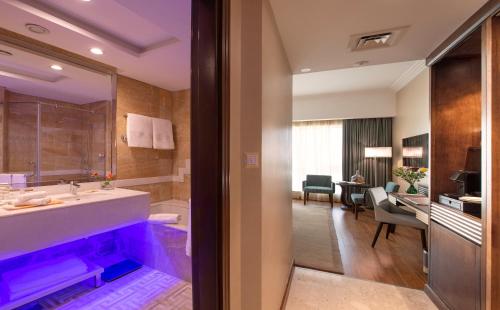 a bathroom with a sink and a living room at Stella Di Mare Dubai Marina Hotel in Dubai