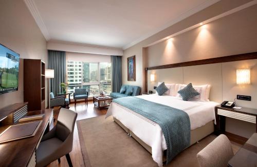ドバイにあるStella Di Mare Dubai Marina Hotelの大きなベッドとデスクが備わるホテルルームです。
