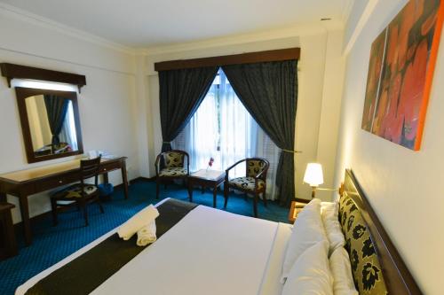 a hotel room with a bed and a desk and a table at Hotel Seri Malaysia Melaka in Melaka
