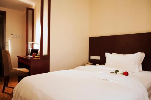 a bedroom with a large white bed and a desk at Xijiao Hotel Beijing in Beijing