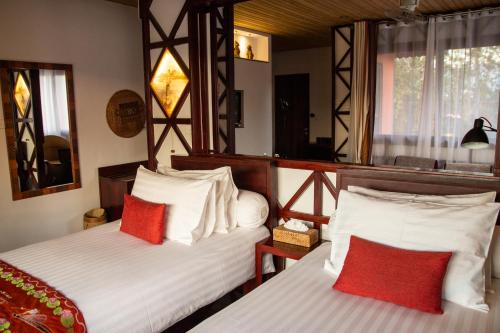 a bedroom with two beds with red and white pillows at ViewPoint Ecolodge in Nyaung Shwe