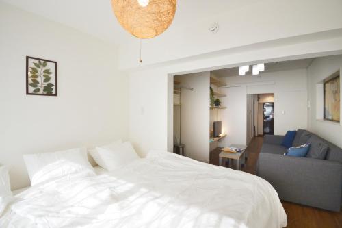 a bedroom with a white bed and a couch at Roppongi Japan House602 in Tokyo