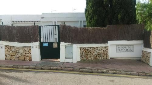 a building with a stone retaining wall with a black door at Beach Suite Playa Cala dor in Cala d´Or