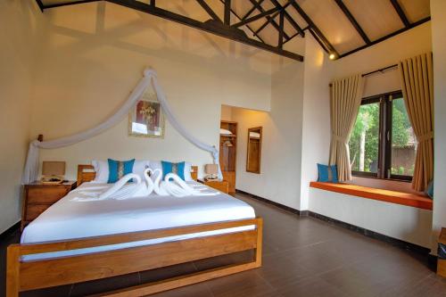 a bedroom with a large white bed with blue pillows at Bintan Spa Villa Beach Resort & Spa in Telukbakau