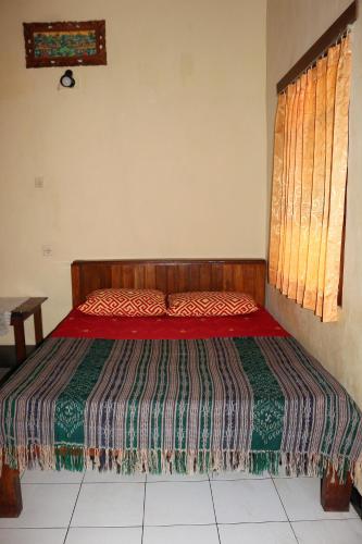 a bedroom with a bed with a red comforter at Arjuna Homestay Ubud in Ubud