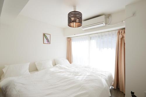 1 cama blanca en un dormitorio con ventana en Roppongi Cat House601, en Tokio