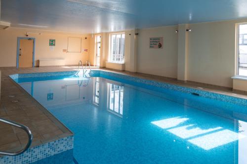 uma grande piscina com água azul num edifício em Shanklin Hotel em Shanklin