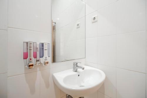 een witte badkamer met een wastafel en een spiegel bij RedDoorz Plus @ Karebosi Area 2 in Makassar