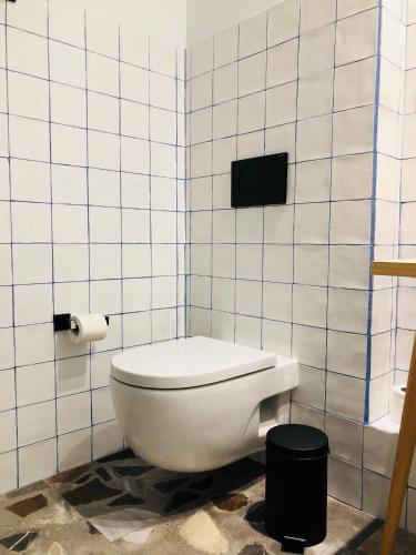 a bathroom with a toilet in a white tiled wall at Casa Vaganto in Barcelona