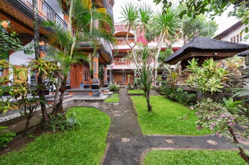 a garden in front of a building with palm trees at Sayong House in Ubud