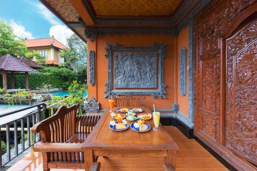 a wooden table with plates of food on a balcony at Sayong House in Ubud