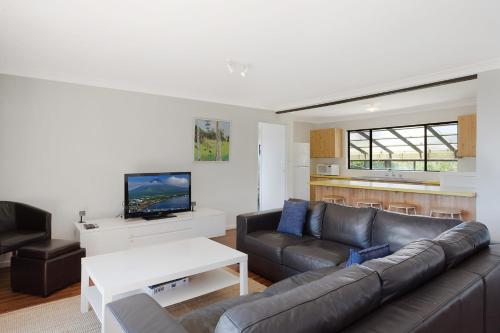 a living room with a couch and a tv at 74 Ocean Parade in Dalmeny