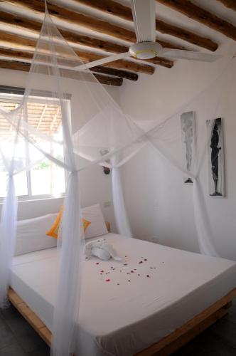 a bedroom with a white bed with confederate at Maisha Marefu Apartments in Kiwengwa