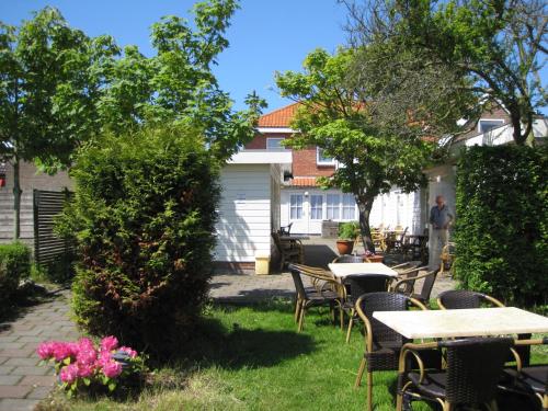a patio with tables and chairs in a yard at Hotel Valkenhof in Zoutelande