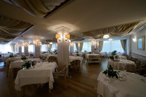 a restaurant with tables and chairs with white tablecloths at Hotel Greif in Lignano Sabbiadoro