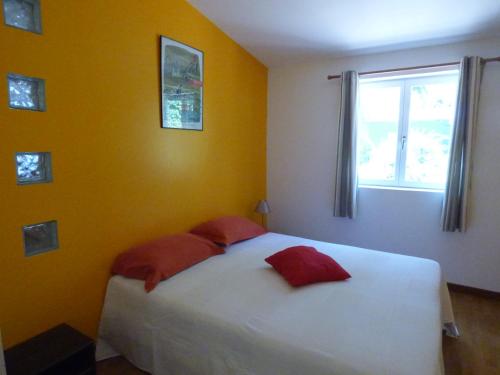 Un dormitorio con una cama blanca con almohadas rojas y una ventana en Gîte de Preuilly en Auxerre