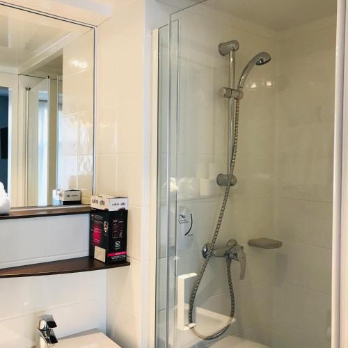 une salle de bain avec une douche avec une porte vitrée dans l'établissement SmartAppart Saint Nazaire, à Saint-Nazaire