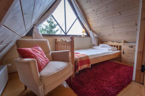 a bedroom with a bed and a chair and a window at Gościniec i Herbaciarnia Pod Złotą Łyżwą in Białka Tatrzanska