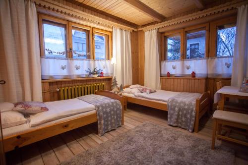 a room with two beds in a room with windows at Gościniec i Herbaciarnia Pod Złotą Łyżwą in Białka Tatrzańska