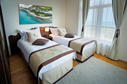 a hotel room with two beds and a window at Thracian Cliffs Golf & Beach Resort in Kavarna