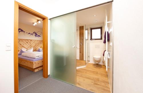 un baño con una puerta de cristal que conduce a un dormitorio en Gästehaus Alpina, en Bad Kohlgrub