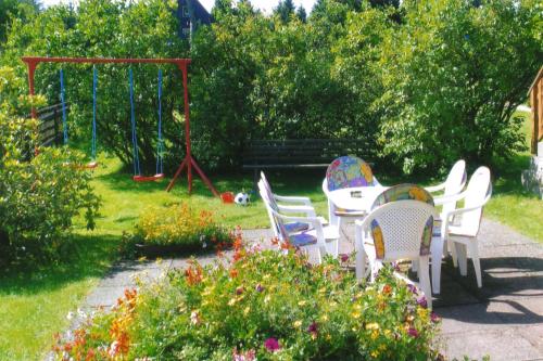 - un jardin avec une table, des chaises et une balançoire dans l'établissement Ferienwohnung im Dachgeschoss _ He, à Neuhermsdorf