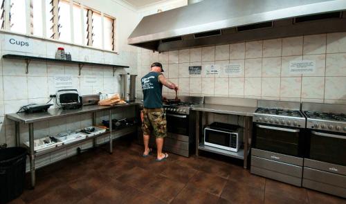 a man standing in a kitchen preparing food at The Hive Hostel in Perth