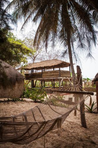 a hammock on the beach under a palm tree at Gîte du Lac in Niaga