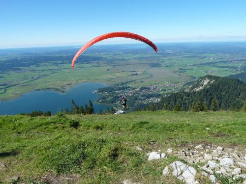 a person flying a parachute on top of a hill at Gästehaus Alpina in Bad Kohlgrub
