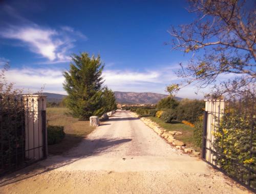 a dirt road with a gate and trees on it at Villas de La Ferme Du Gros Noyer in Malaucène