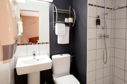 La salle de bains est pourvue de toilettes, d'un lavabo et d'une douche. dans l'établissement Cit'Hotel de la Marne, à Tarbes